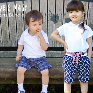 May include: Two children wearing shorts. A boy is wearing plaid shorts and a white shirt. A girl is wearing navy blue and white patterned shorts with a white shirt and a red and white gingham belt. The text "Oscar & Maisy Shorts Bundle" is at the top of the image.
