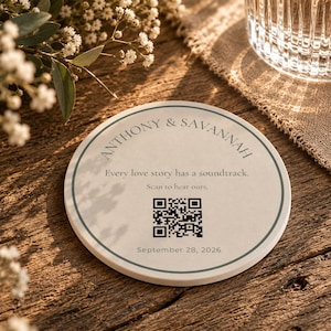 May include: A round, off-white ceramic coaster featuring a dark green circular border. The text reads ANTHONY & SAVANNAH, Every love story has a soundtrack. Scan to hear ours., and September 28, 2026. A black QR code is printed in the center.