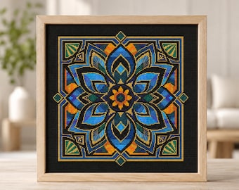 May include: A square cross-stitch embroidery featuring a symmetrical mandala pattern with blue, orange, and green threads on a black background, encased in a light-colored wooden frame. The design displays a central flower motif.