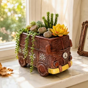 May include: A brown, van-shaped planter featuring a yellow front bumper, white daisy decals, and a peace sign emblem. The planter is filled with a variety of green succulents, including trailing string of pearls and several pebble-like lithops.