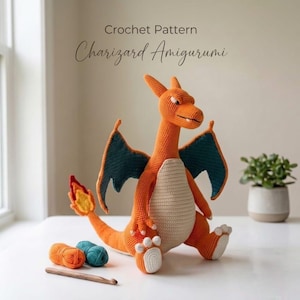 May include: A crochet pattern for a Charizard amigurumi featuring a handmade orange dragon with teal wings, a cream-colored belly, and a flame on its tail. The image includes text reading Crochet Pattern Charizard Amigurumi, two yarn balls, and a wooden hook.