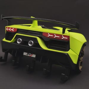 May include: A lime green wall-mounted key holder shaped like the rear of a sports car. It features a black spoiler, two silver exhaust pipes, red taillights, and a number plate with the letters SV. Five black hooks extend from the bottom.