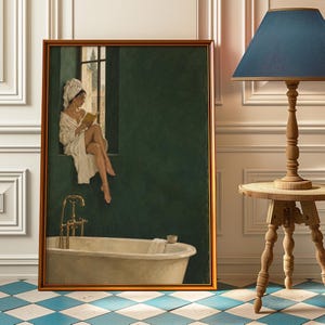 May include: A framed wall art print depicting a person in a white bathrobe and hair towel sitting on a window ledge reading a book above a white bathtub with gold fixtures. The painting features a deep green wall and a view of a building exterior.