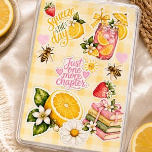 Könnte beinhalten: Eine transparente Kindle-Hülle mit gelbem Vichy-Karo-Hintergrund, verziert mit Aufklebern wie einer Erdbeere, einer Zitrone, einer Biene, einem Glas rosa Limonade, einem Bücherstapel, einem Gänseblümchen und dem Text Squeeze the day und Just one more chapter.