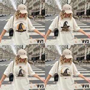 May include: A beige baseball cap and a cream-colored t-shirt featuring a graphic print of a witch hat with the text Stay Magical. The design includes celestial elements like moons and stars, presented in four variations with different hat placements.