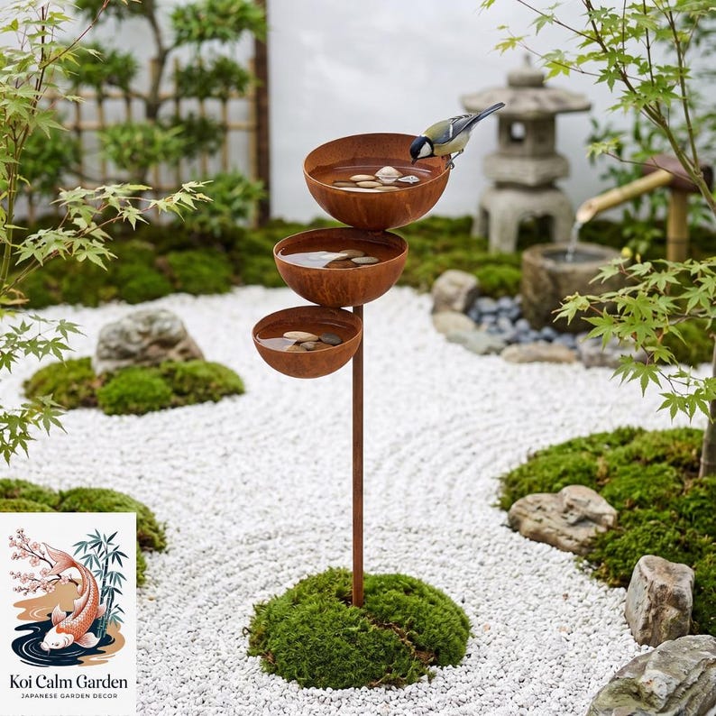 May include: A tiered bird bath featuring three stacked, rust-colored metal bowls supported by a single vertical pole. Each bowl contains water and small, smooth river stones. A small bird with yellow and black markings perches on the top bowl.
