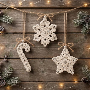 May include: Three cream-colored crocheted ornaments hanging from a string, including a candy cane, a six-pointed snowflake, and a five-pointed star. Each ornament is embellished with small, clear, reflective beads and a single white pearl bead.