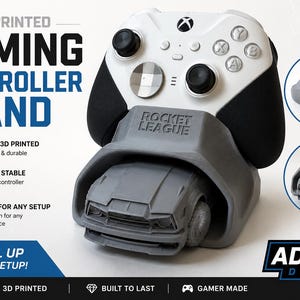 May include: A gray 3D printed gaming controller stand featuring a Rocket League car design. The stand holds a white and black wireless gaming controller. The text Rocket League is embossed on the front of the stand. Additional circular insets show the stand from different angles. The overall design is functional and displays the controller securely.