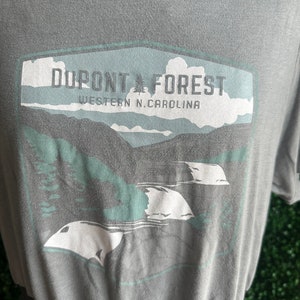 May include: A gray t-shirt with a graphic print of a mountain range and the text "DUPONT FOREST WESTERN N.CAROLINA".