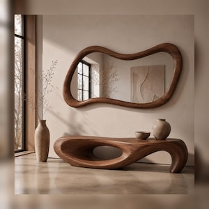 Peut inclure: Un miroir mural en bois foncé avec un cadre irrégulier, organique et ondulé. Sous le miroir se trouve un banc en bois foncé assorti présentant un design lisse, incurvé et bas avec une ouverture centrale et une extrémité arrondie.