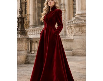 Könnte beinhalten: Ein bodenlanges Mantelkleid aus tiefrotem Samt mit Stehkragen, langen Ärmeln und einem taillierten Oberteil, das in einen weiten, fließenden Rock übergeht. Das Kleidungsstück ist strukturiert geschnitten und verfügt über seitliche Eingrifftaschen.