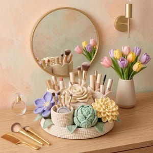 May include: A beige crocheted makeup organizer tray featuring integrated cylindrical holders and decorative fabric flowers in purple, yellow, and green. The organizer contains various makeup brushes and lipsticks, accompanied by a comb and perfume bottle.