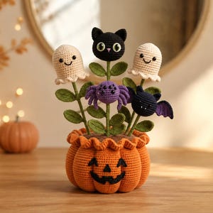 May include: A crocheted pumpkin-shaped pot with a jack-o'-lantern face containing a bouquet of yarn figures. The arrangement features two cream-colored ghosts, a black cat head, a purple spider, and a small black bat on green stems with leaves.