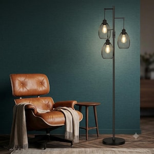 May include: A tall black metal floor lamp featuring a thin central pole and a round base. The lamp has three cage-style shades arranged at different heights, each containing a glowing light bulb that emits a warm light into the room.