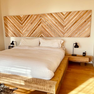 May include: A wooden platform bed frame with a white duvet and two pillows. The headboard is made of wood planks arranged in a chevron pattern.