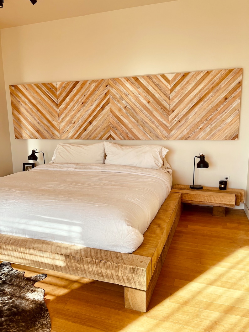 May include: A wooden platform bed frame with a white duvet and two pillows. The headboard is made of wood planks arranged in a chevron pattern.