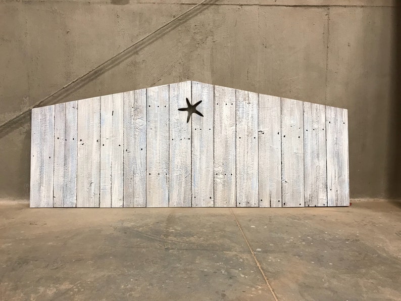 Puede incluir: Estructura de madera blanqueada que se asemeja a un granero con un recorte en forma de estrella de mar en el centro. La estructura est&aacute; de pie sobre un suelo de hormig&oacute;n.
