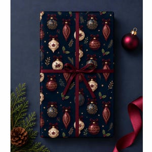 May include: A rectangular gift box wrapped in dark navy blue paper featuring a repeating pattern of red, gold, and cream-colored Christmas ornaments and sprigs of holly. The box is tied with a dark red satin ribbon in a centered bow.