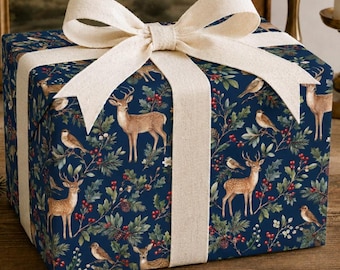 Può includere: Una scatola regalo quadrata avvolta in carta blu scuro con un motivo ripetuto di cervi marroni, piccoli uccelli, foglie di agrifoglio verdi e bacche rosse. La scatola è legata con un ampio nastro in tessuto color crema dalla trama ruvida.