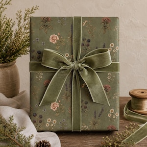 Pu&ograve; includere: Una scatola regalo rettangolare avvolta in carta verde salvia con una stampa botanica di piccoli fiori, bacche e foglie. La scatola &egrave; legata con un ampio nastro di velluto verde salvia annodato in un grande fiocco centrato sul davanti.