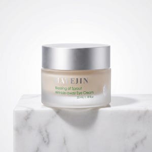 Könnte beinhalten: Ein zylindrischer Tiegel Hayejin Blessing of Sprout Wrinkle-away Augencreme mit silbernem Deckel und mattem Glasboden. Das Etikett trägt dunkelgrünen und silbernen Text und gibt ein Volumen von 35 ml / 1,18 fl. oz. auf der Vorderseite an.