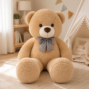 Pode incluir: Um grande urso de peluche com pelo macio castanho claro, orelhas redondas e um nariz castanho escuro. O urso apresenta uma zona de focinho branca e uma gravata borboleta aos quadrados pretos e brancos ao pescoço. Tem olhos redondos.