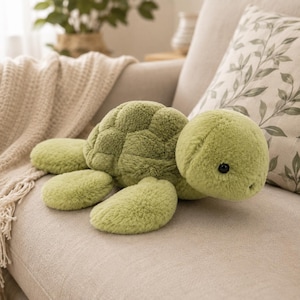 May include: A plush turtle toy featuring soft, light green faux fur. The stuffed animal has a rounded shell with a segmented, textured pattern, four flipper-like limbs, and a smooth, rounded head with small, dark, circular eyes.