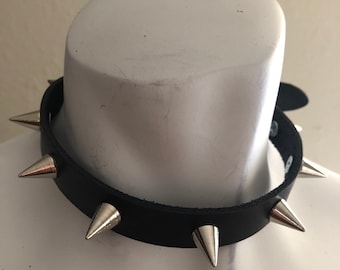 Op de afbeelding: Een zwarte leren choker met zilveren spikes. De choker is op een wit mannequin.