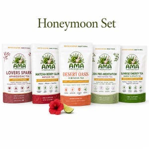 May include: Five white pouches of Ama Remedies tea labeled Honeymoon Set, including Lovers Spark, Matcha Berry Glow, Desert Oasis, Zen Pre-Meditation, and Sunrise Energy. Each 3.53 oz pouch features botanical illustrations, icons, and text.