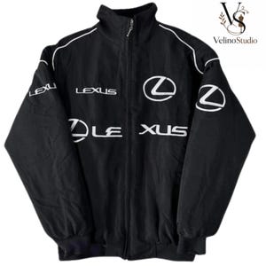 Puede incluir: Una chaqueta negra con cremallera, cuello alto y ribetes blancos en los hombros. La parte delantera y las mangas están decoradas con logotipos y texto de la marca Lexus en blanco. La chaqueta tiene mangas largas con puños acanalados y cremallera.