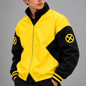 Three-quarter view of men's yellow and black zip-up bomber jacket with black sleeves and X patch, studio gray background