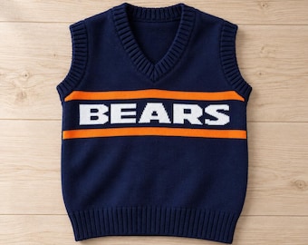May include: A navy blue sleeveless knit sweater vest with a V-neckline and ribbed trim. The front features a horizontal orange stripe pattern with the word BEARS printed in large white capital letters across the center of the chest.