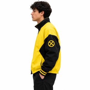 Side profile of men's yellow and black bomber jacket with X patch on sleeve and yellow striped ribbed cuff