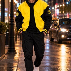 Man wearing yellow and black bomber jacket at night on a wet city street with car lights, urban streetwear style