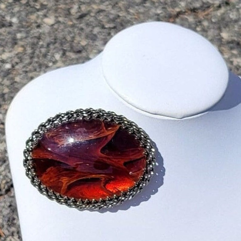 This listing is for a gorgeous statement brooch. It is a large golden glass oval shaped pin with lots of fire.