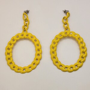 May include: A pair of yellow hoop earrings with a chain link design. The earrings are made of metal and have a shiny finish.