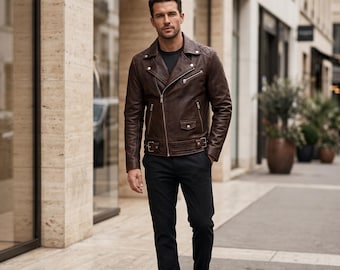 Può includere: Una giacca da moto in pelle marrone scuro con bavero, cerniere in metallo color argento, una piccola tasca con patta e una cintura regolabile in vita, indossata sopra una maglietta a girocollo con pantaloni scuri e stivali in pelle nera.
