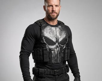 Può includere: Un gilet tattico nero con una grande grafica a teschio bianco dall'aspetto usurato sul petto. Il gilet include diverse tasche integrate, cinghie regolabili e un design modulare. È indossato sopra una maglia nera a maniche lunghe.
