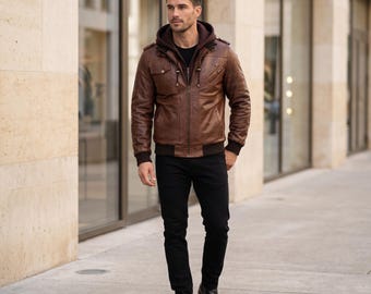 Può includere: Una giacca in pelle marrone con inserto a cappuccio marrone scuro, cerniera frontale e tasche multiple. La giacca presenta polsini e orlo a coste, abbinata a pantaloni neri e stivaletti in pelle nera per un look a strati.
