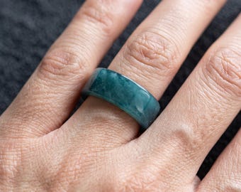 May include: A wide band ring featuring a smooth, polished surface with a deep teal and blue-green marbled appearance. The ring has a solid, continuous construction with a glossy finish that reflects light across its curved, cylindrical exterior surface.