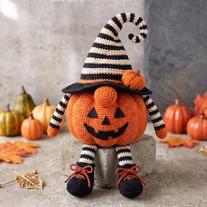 Peut inclure: Un gnome citrouille au crochet avec un corps orange en forme de lanterne, coiffé d'un chapeau pointu rayé noir et blanc. Il possède des jambes pendantes avec des bas rayés et des chaussures noires à lacets orange, orné d'une petite citrouille.