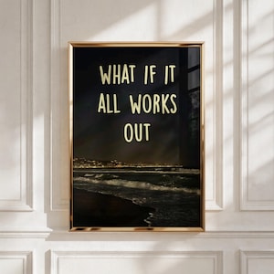 Könnte beinhalten: Ein rechteckiger Wandkunstdruck in einem dünnen goldenen Rahmen zeigt eine nächtliche Szene eines dunklen Ozeans mit Wellen, die an das Ufer schlagen, und entfernten Stadtlichtern. Der Text WHAT IF IT ALL WORKS OUT ist in hellgelber Schrift.