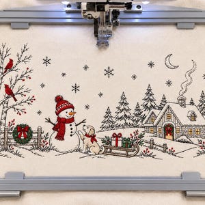 May include: An embroidery hoop containing fabric with a winter scene featuring a snowman, a puppy, a house with a smoking chimney, a tree with two red birds, a lamppost, and falling snowflakes, all stitched in black, white, and red thread.
