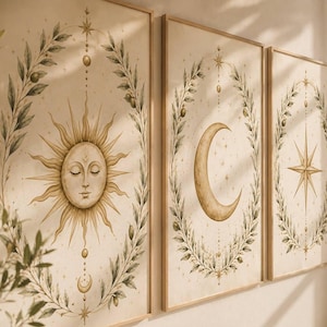 May include: A set of three framed wall art prints featuring a sun with a face, a crescent moon, and a star, each centered within an oval wreath of green olive branches and small gold spheres on a light beige background with gold accents.