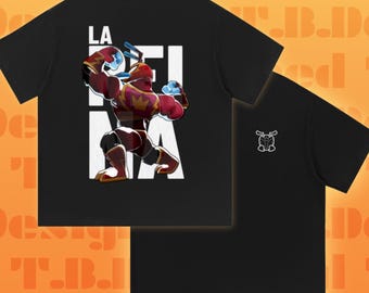 May include: A black short-sleeve t-shirt featuring a graphic of a muscular red and gold character in a boxing pose over the white text LA REINA. The back of the shirt displays a small white line-art icon of a helmeted character head on the chest.
