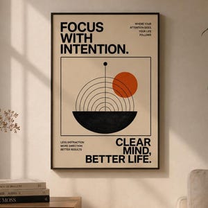 May include: A rectangular wall art print on a beige background featuring black text that reads FOCUS WITH INTENTION, CLEAR MIND, BETTER LIFE, and smaller phrases. A black semi-circle with concentric lines and an orange circle are centred.
