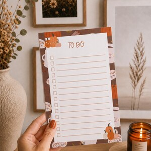 May include: A rectangular to-do list notepad with a brown border featuring illustrations of orange pumpkins and coffee mugs. The white centre section contains the text TO DO at the top, followed by twelve horizontal lines with empty checkboxes.