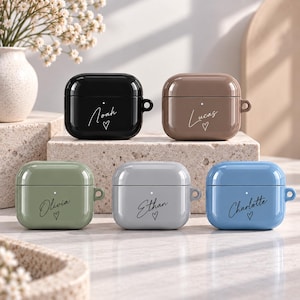 May include: Five glossy, rounded earbud cases in black, brown, sage green, light gray, and blue. Each case features a small LED indicator light, a side loop, and a custom name printed in cursive script above a small hand-drawn heart icon.