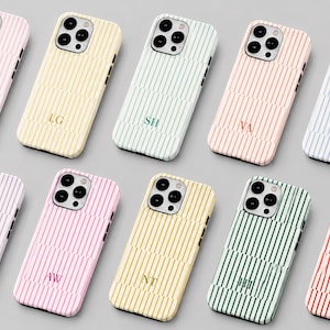 May include: A collection of ten rectangular phone cases arranged in two rows, each featuring a vertical striped pattern in various pastel and bold colors. Each case displays a unique two-letter monogram centered on the lower half of the back.