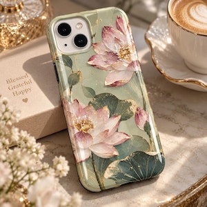 May include: A sage green phone case featuring a detailed illustration of pink lotus flowers and dark green lily pads with gold foil accents. The design includes two large blooming lotus flowers and a smaller bud, all accented with gold leaf details.